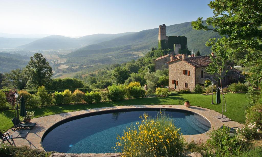 a pool in a yard with a house and mountains at Rocca Di Pierle Agriturismo di Charme in Mercatale