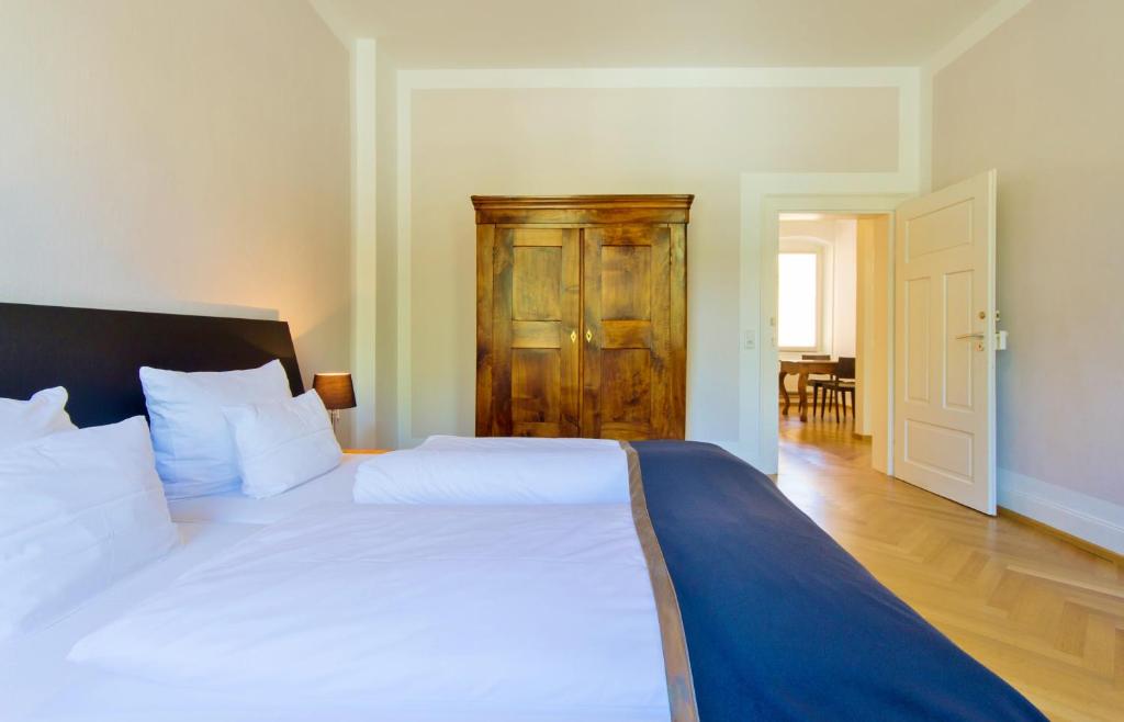ハイデルベルクにあるQube Apartments Bergheimの白いベッド1台、木製のドアが備わるベッドルーム1室が備わります。