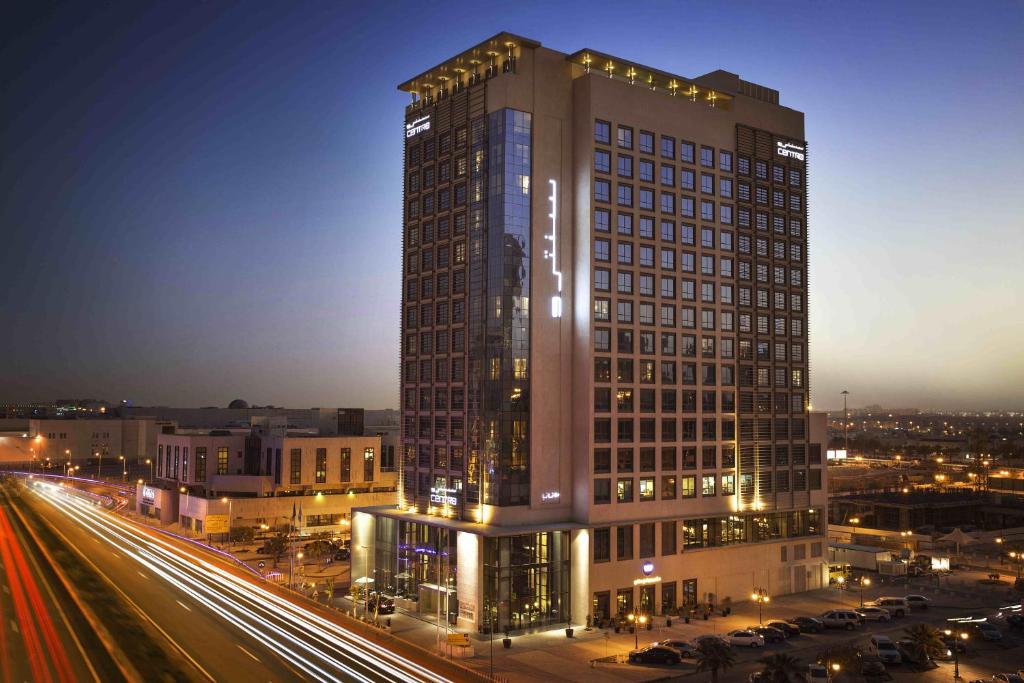 a tall building with lights on it next to a street at Centro Waha by Rotana in Riyadh