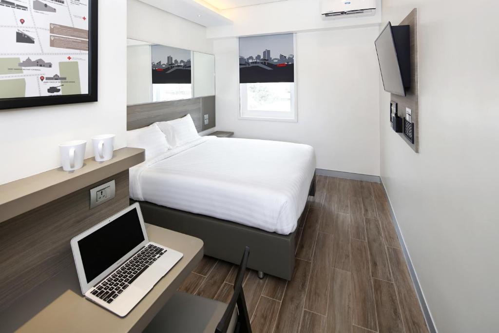 a hotel room with a bed and a laptop on a desk at Red Planet Cubao Aurora Boulevard in Manila