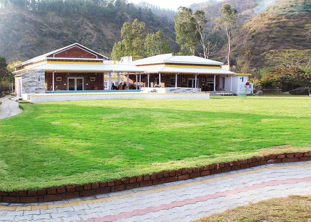 une maison avec une pelouse verte devant dans l'établissement Four Banyans Spirit & Nature Resort, à Rāipur