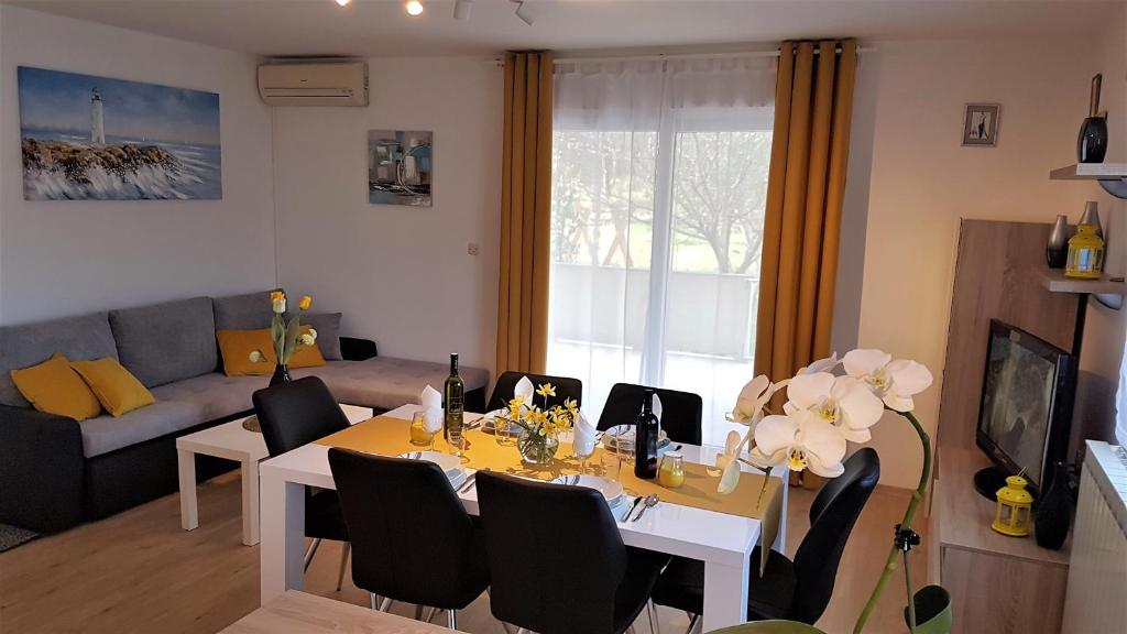 uma sala de estar com uma mesa de jantar com cadeiras em Apartment Grašo em Rab