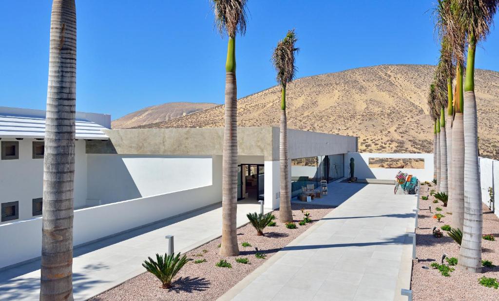 a building with palm trees in front of a mountain at INNSiDE by Meliá Fuerteventura – Adults Only in Costa Calma
