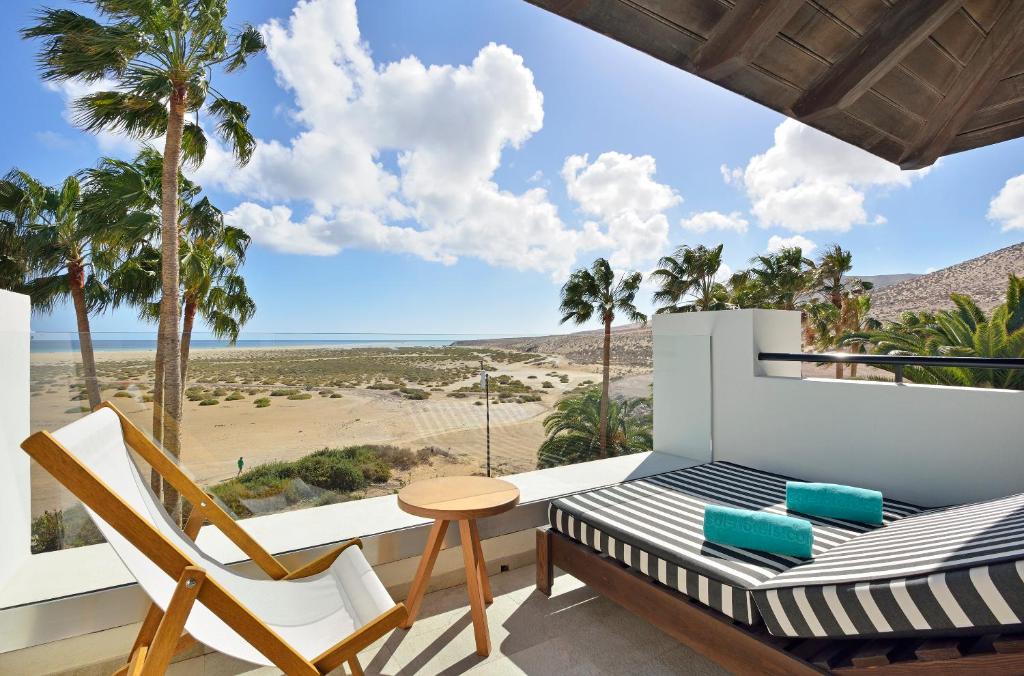 a balcony with a bed and chairs and a view of the beach at INNSiDE by Meliá Fuerteventura – Adults Only in Costa Calma