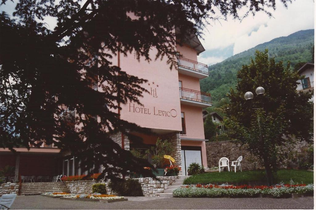 un gran edificio rosa con sillas delante en Hotel Levico, en Levico Terme