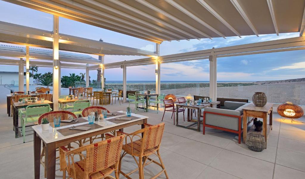 a restaurant with tables and chairs and a view of the ocean at INNSiDE by Meliá Fuerteventura – Adults Only in Costa Calma