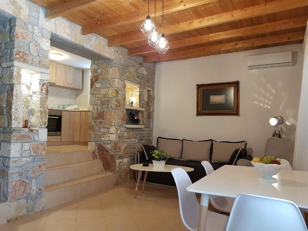 ナフプリオにあるNafplio cozy mountain cottageの石壁のリビングルーム(テーブル付)
