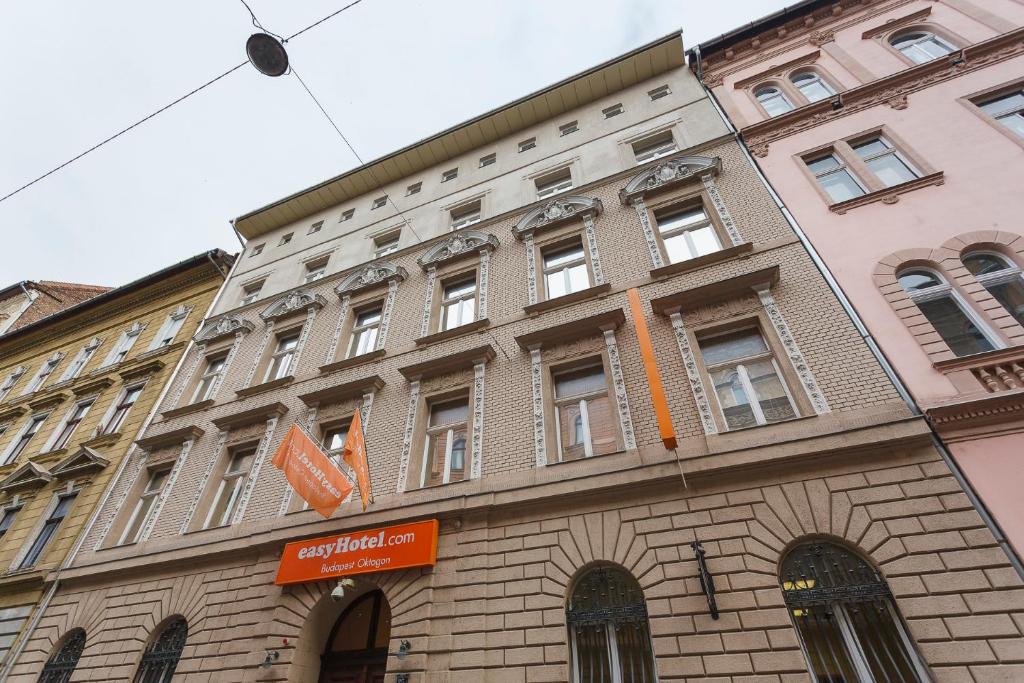 a large brick building with an orange sign on it at easyHotel Budapest Oktogon in Budapest