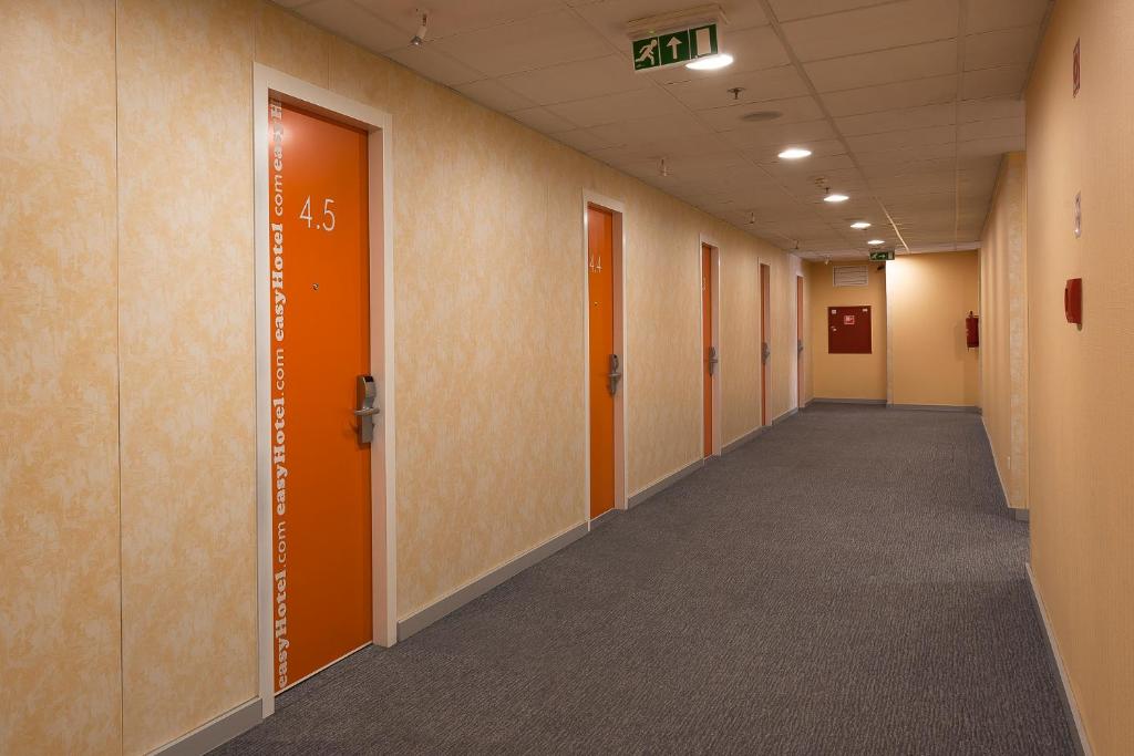 an empty hallway of an office building with orange doors at easyHotel Budapest Oktogon in Budapest