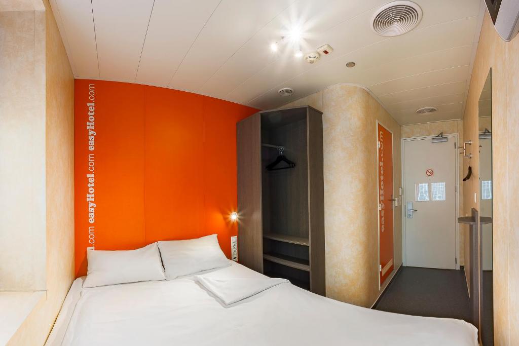 a bed in a room with an orange wall at easyHotel Budapest Oktogon in Budapest