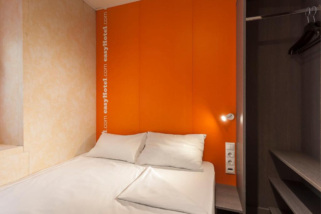 a bed in a room with an orange wall at easyHotel Budapest Oktogon in Budapest