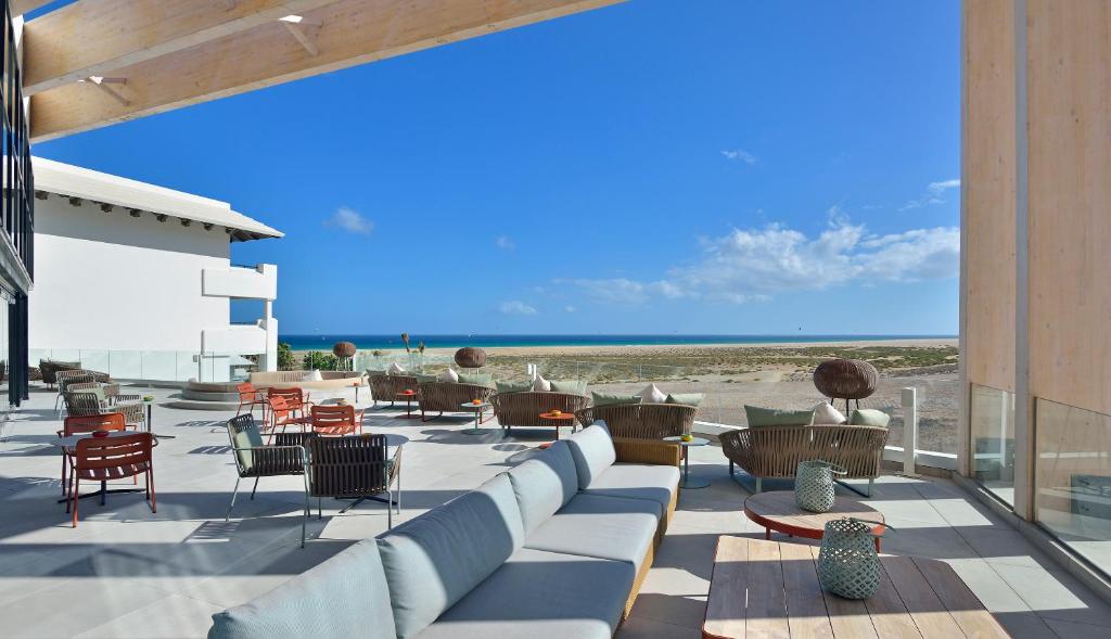a patio with a couch and chairs and the beach at INNSiDE by Meliá Fuerteventura – Adults Only in Costa Calma
