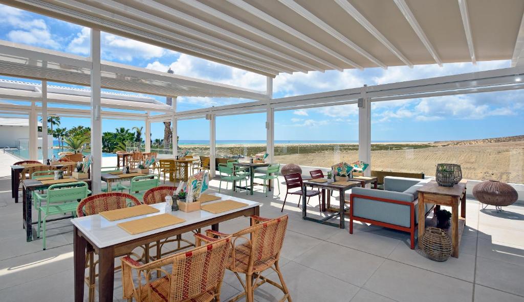 a restaurant with tables and chairs and windows at INNSiDE by Meliá Fuerteventura – Adults Only in Costa Calma