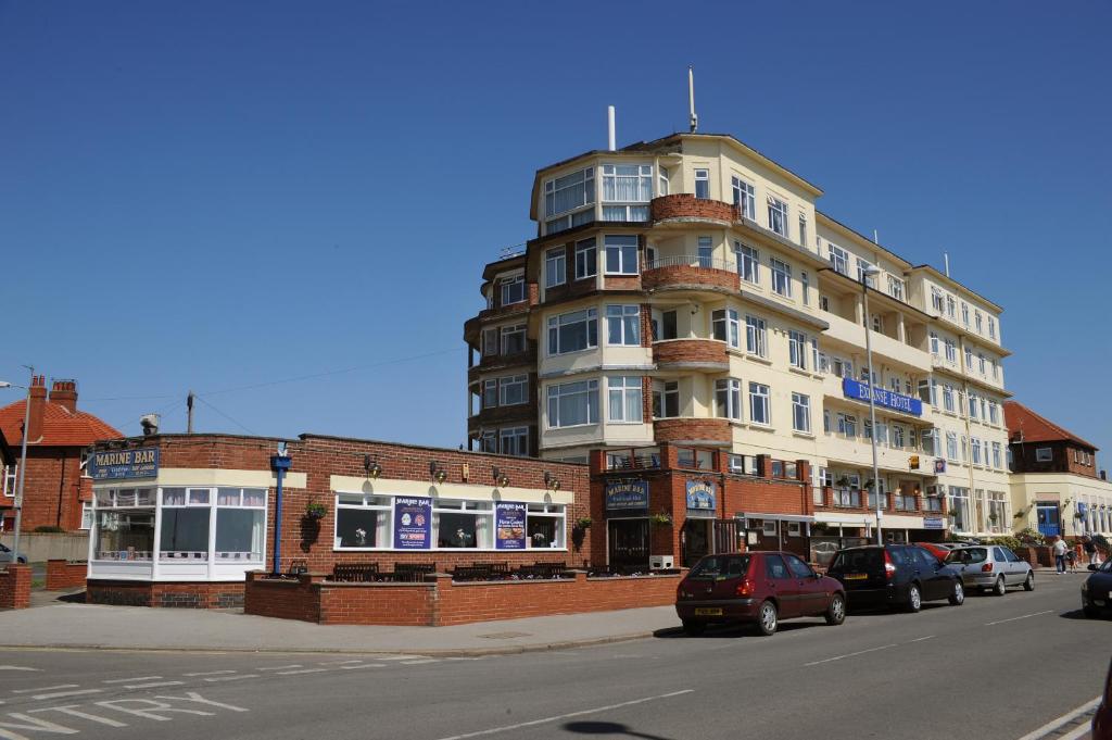 wysoki budynek z samochodami zaparkowanymi przed ulicą w obiekcie Expanse Hotel w mieście Bridlington