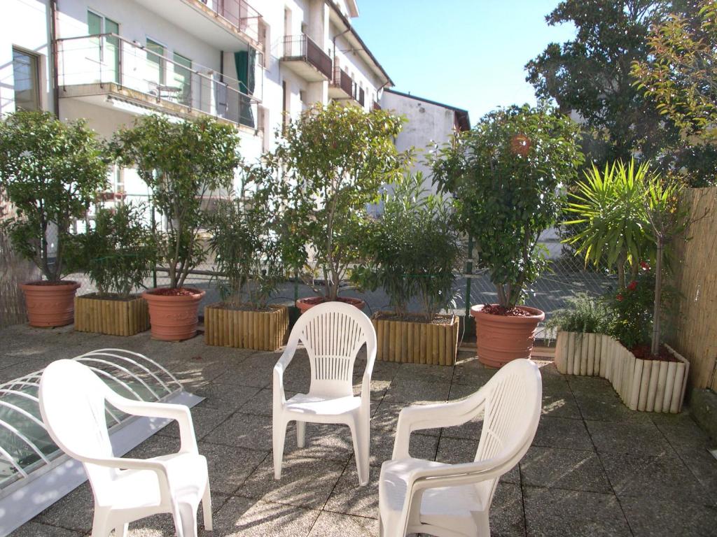 three white chairs sitting on a patio with trees at Galleria Excelsior in Grado