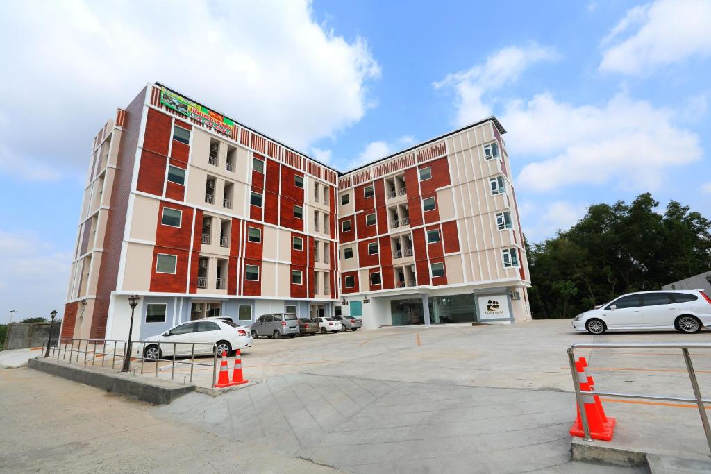 a large building with cars parked in a parking lot at Triple Trees Hotel in Pathum Thani