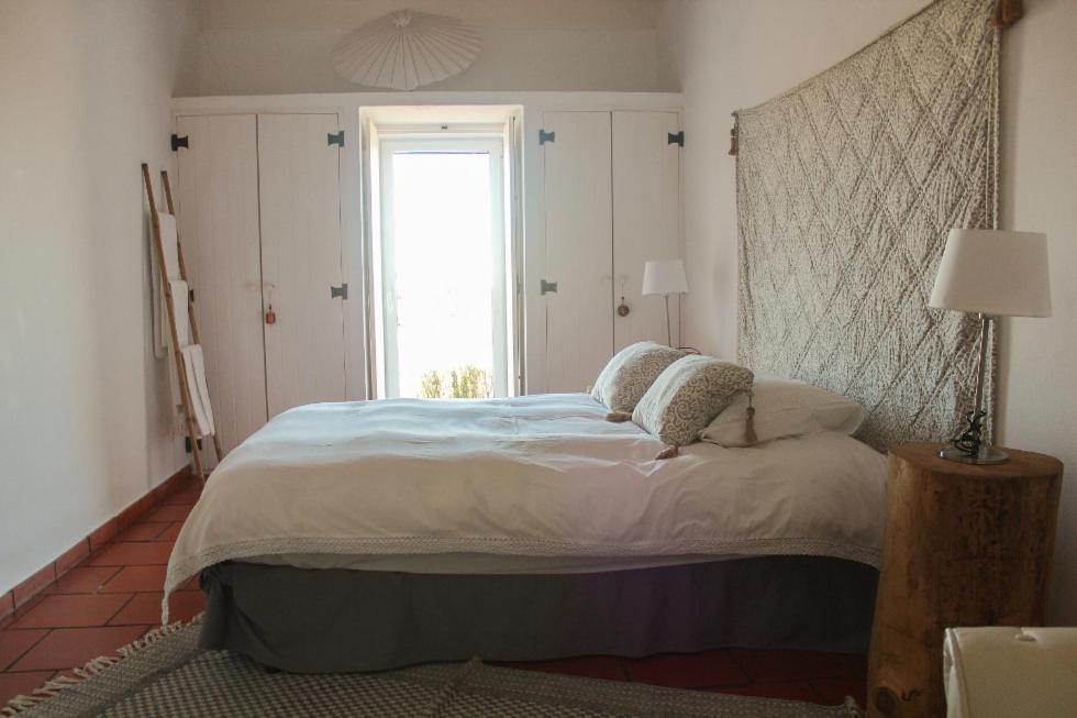 a bedroom with a large bed and a window at Comporta House in Comporta