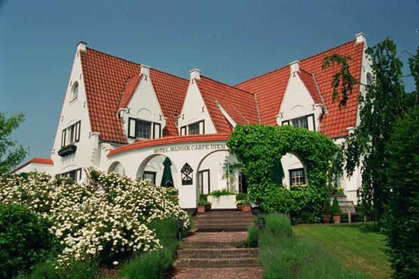una gran casa blanca con techo rojo en Romantik Manoir Carpe Diem en De Haan