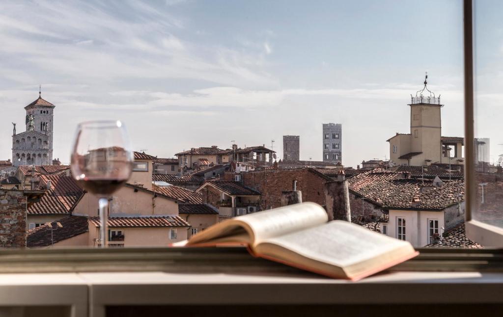 an open book and a glass of wine on a window sill at The Artist's Loft in Lucca