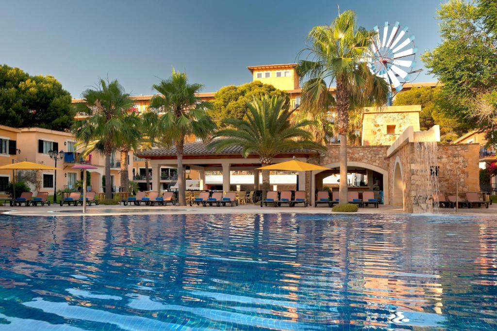 
a large swimming pool in a tropical setting at Occidental Playa de Palma in Playa de Palma
