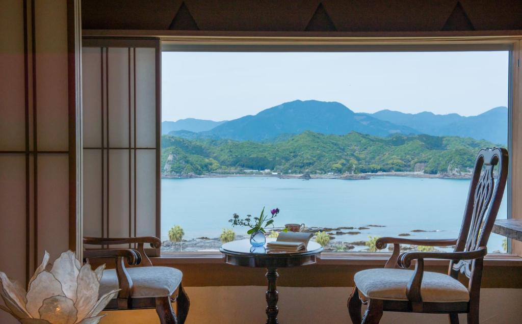 a room with a large window with a table and chairs at Hana Irodori no Yado Kayuu in Taiji