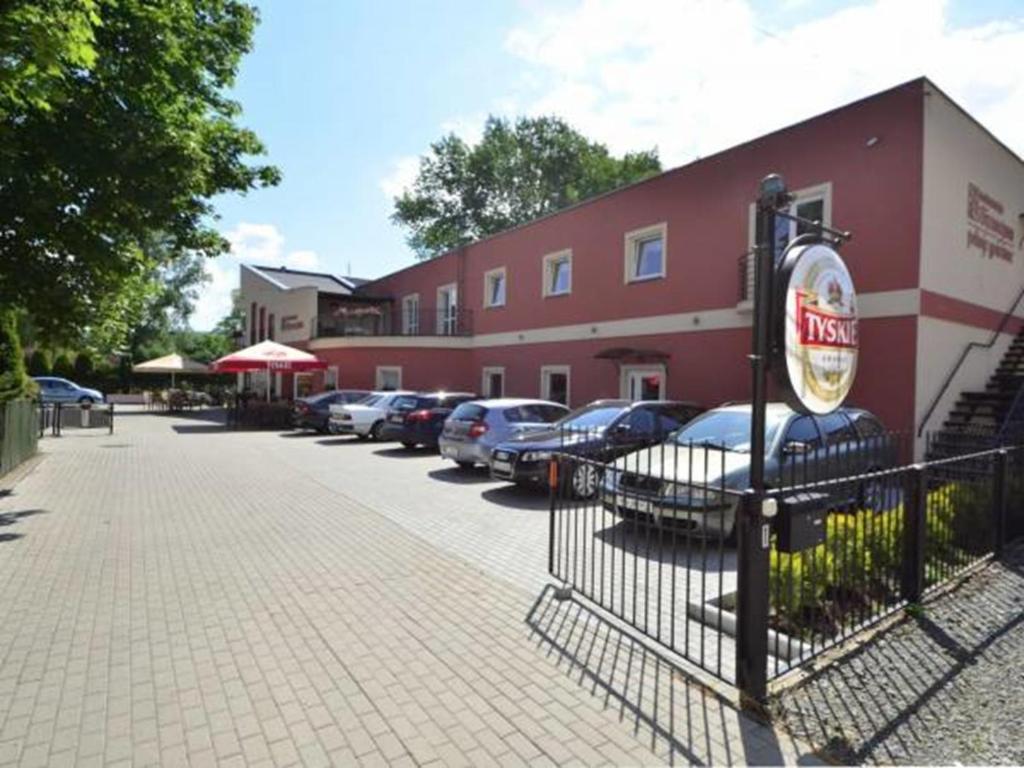 een rood gebouw met auto's geparkeerd op een parkeerplaats bij Bizancjum Pokoje Gościnne PARKING FREE 24H in Kłodzko