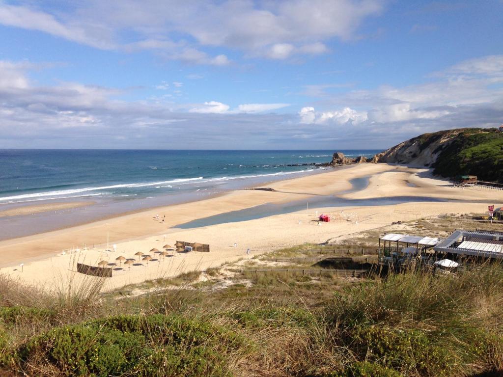 einen Sandstrand mit Sonnenschirmen und dem Meer in der Unterkunft Apartamento acolhedor numa das mais belas praias do centro de Portugal in Pataias