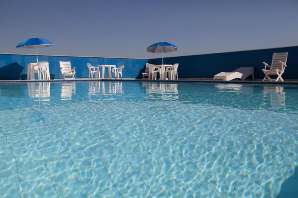 a swimming pool with chairs and umbrellas at Hotel Dan Inn São José dos Campos in São José dos Campos