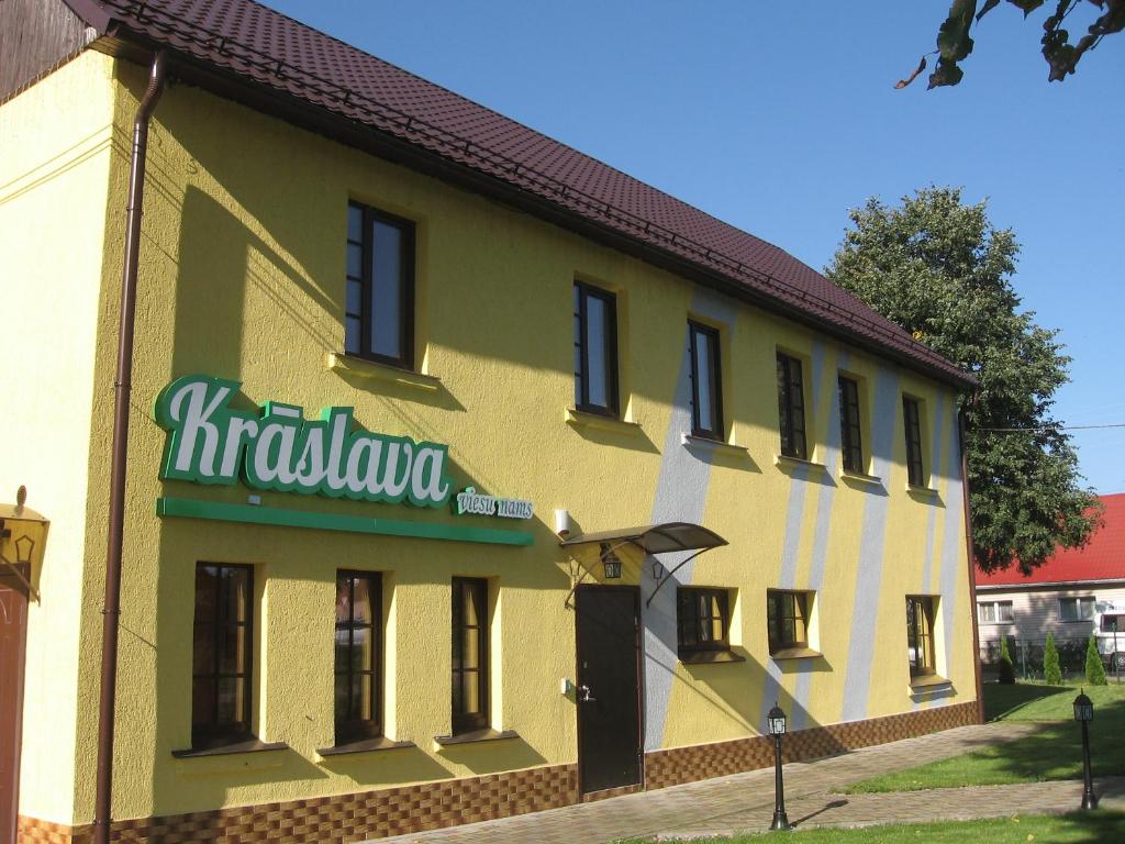 un edificio blanco y amarillo con un letrero. en Hotel in Kraslava, en Krāslava