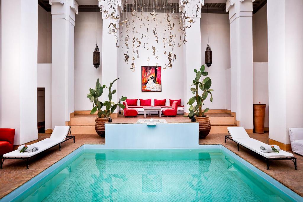 a living room with a pool and a red couch at Hotel & Spa Riad Al Jazira in Marrakech