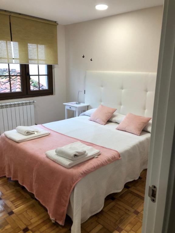 - une chambre avec un grand lit blanc et des oreillers roses dans l'établissement Madala XXI, à Oviedo