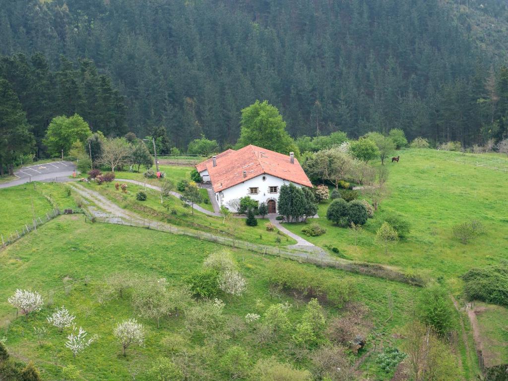 een huis met een rood dak in een groen veld bij Hotel Rural Natxiondo in Lekeitio
