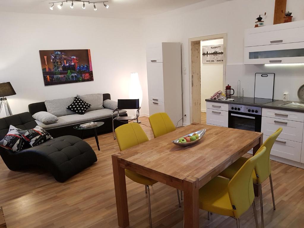 een keuken en een woonkamer met een houten tafel en gele stoelen bij FewoFaubelCentro 42 & 54 & 62 m2 in Oberhausen