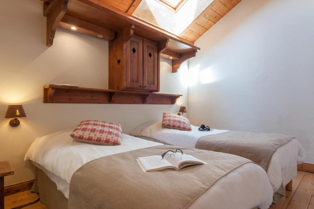 two beds with a book on them in a room at Résidence Pierre & Vacances Premium Les Fermes De Méribel in Méribel