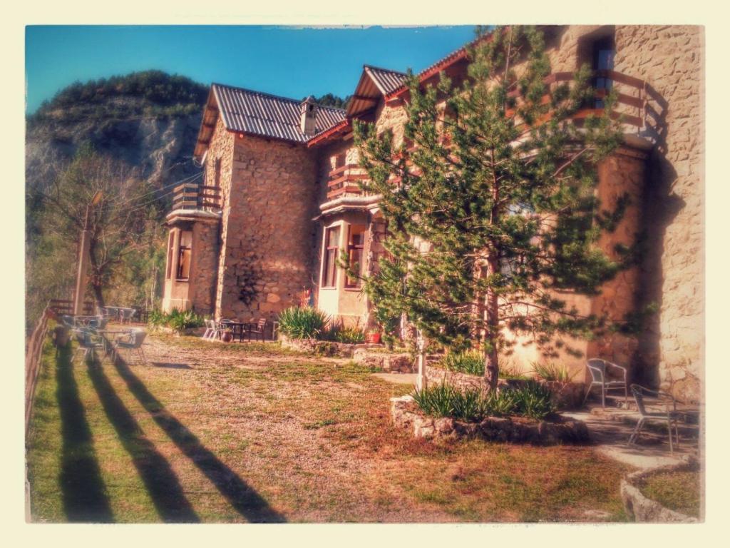 a brick house with a tree in front of it at Refugi Quatre Cases in Clot del Moro