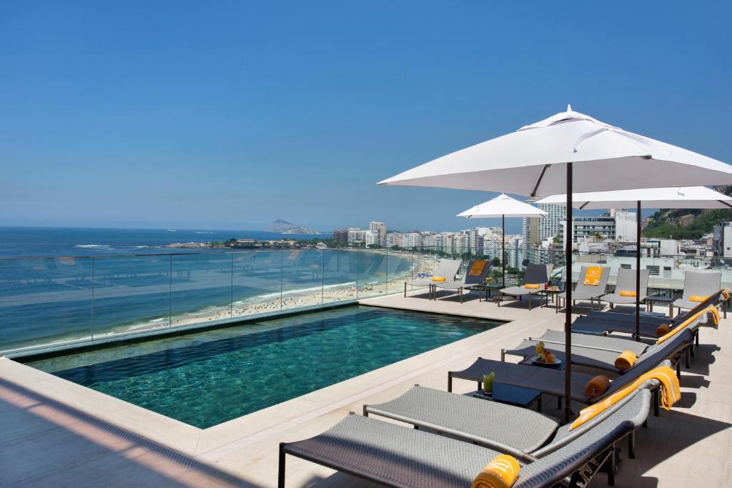 uma piscina com cadeiras e guarda-sóis num edifício em Windsor California Copacabana no Rio de Janeiro