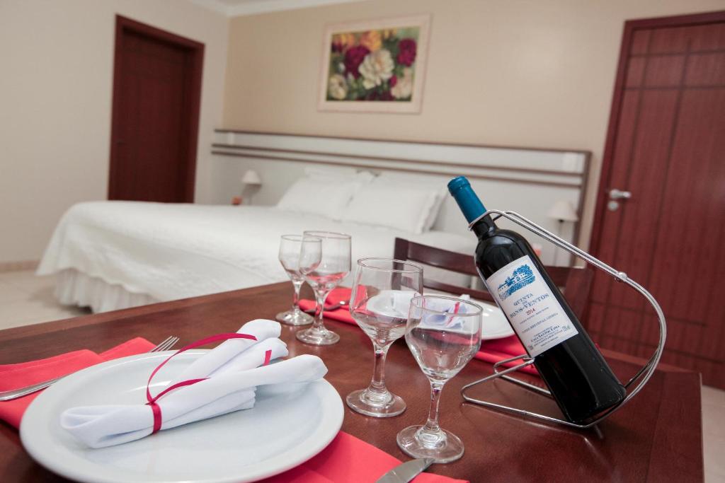 una botella de vino sentada en una mesa con copas en Hotel Dom Baroni en Guarapuava