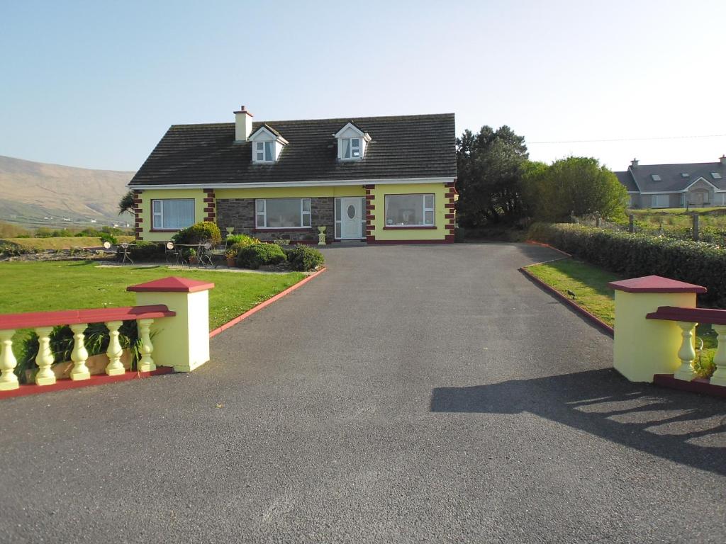 a house with a driveway with two benches in front of it at The Waterfront B&B in Portmagee