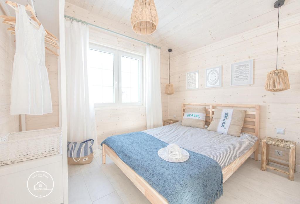 a bedroom with a bed with a blue blanket at Pastelowe Domki Darłówko in Darłówko