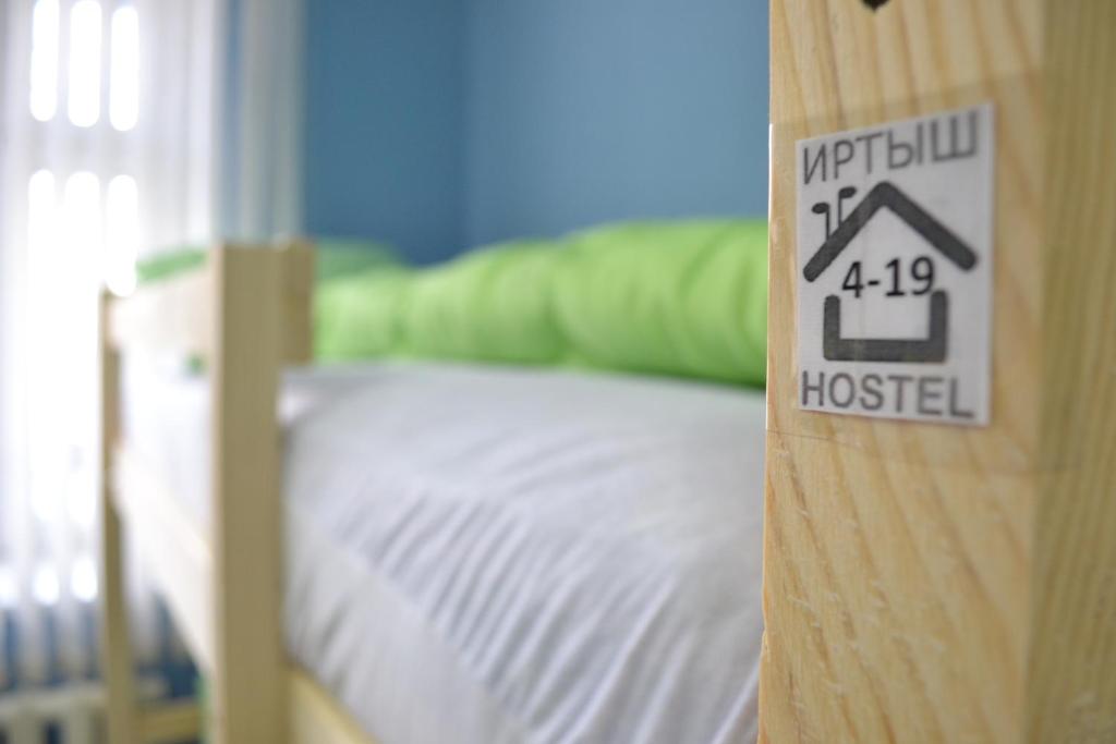 オムスクにあるIrtysh Hostelのベッド1台(ドアに看板付)