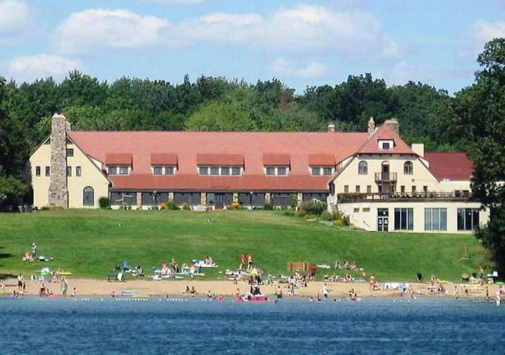 a large building with people on a beach near the water at Potawatomi Inn & Cabins in Angola