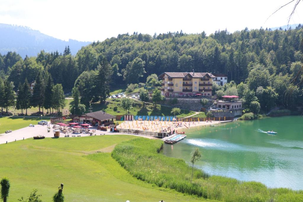 un complejo en un lago con un barco en el agua en Hotel Al Lago, en Lavarone