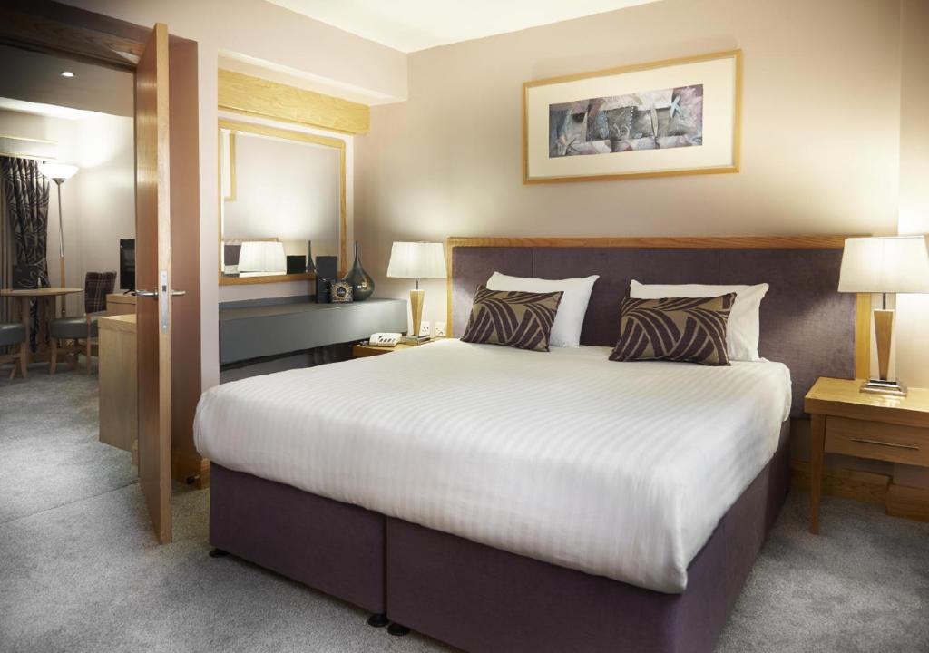 a hotel room with a large bed and a desk at The Suites Hotel & Spa Knowsley - Liverpool by Compass Hospitality in Knowsley