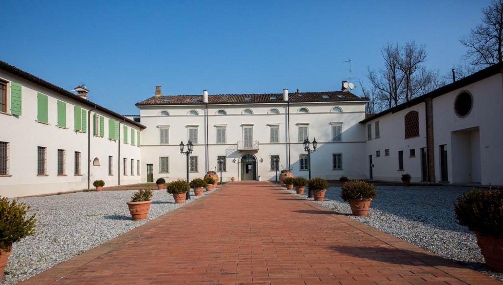 San Giovanni in Croce的住宿－Locanda Ca’ Rossa，一条白色的大建筑,在人行道上种有盆栽植物