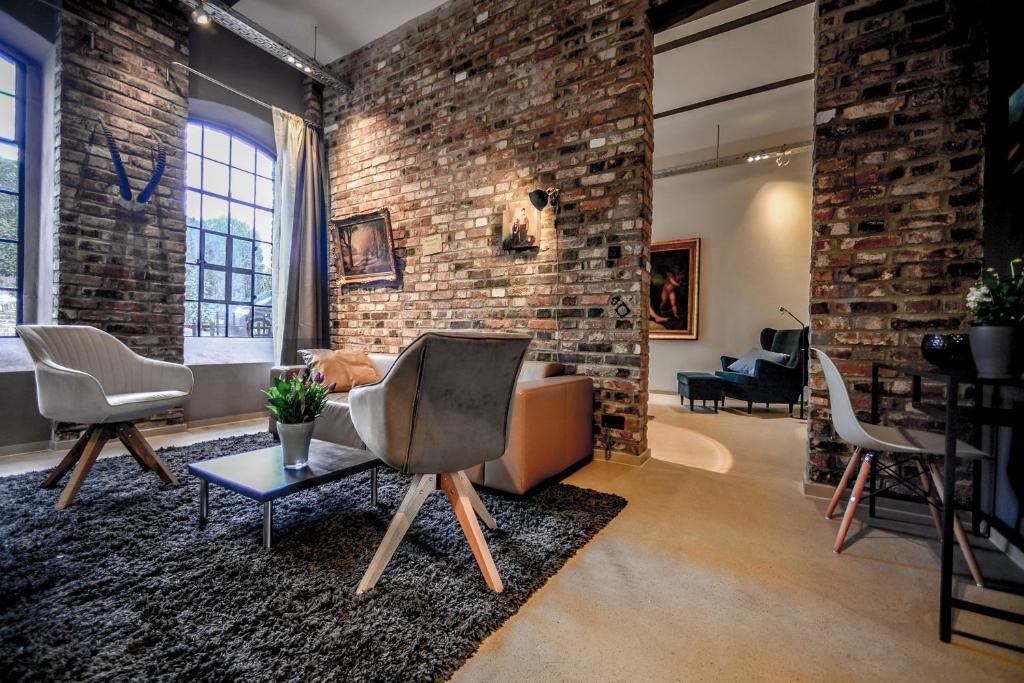 a living room with a brick wall and chairs at Carl-Kaiser-Loft I in Solingen