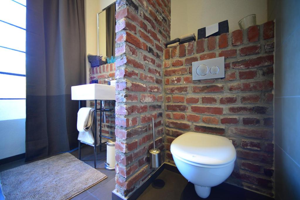 ein Badezimmer mit einer Ziegelwand und einer Toilette in der Unterkunft Carl-Kaiser-Loft I in Solingen