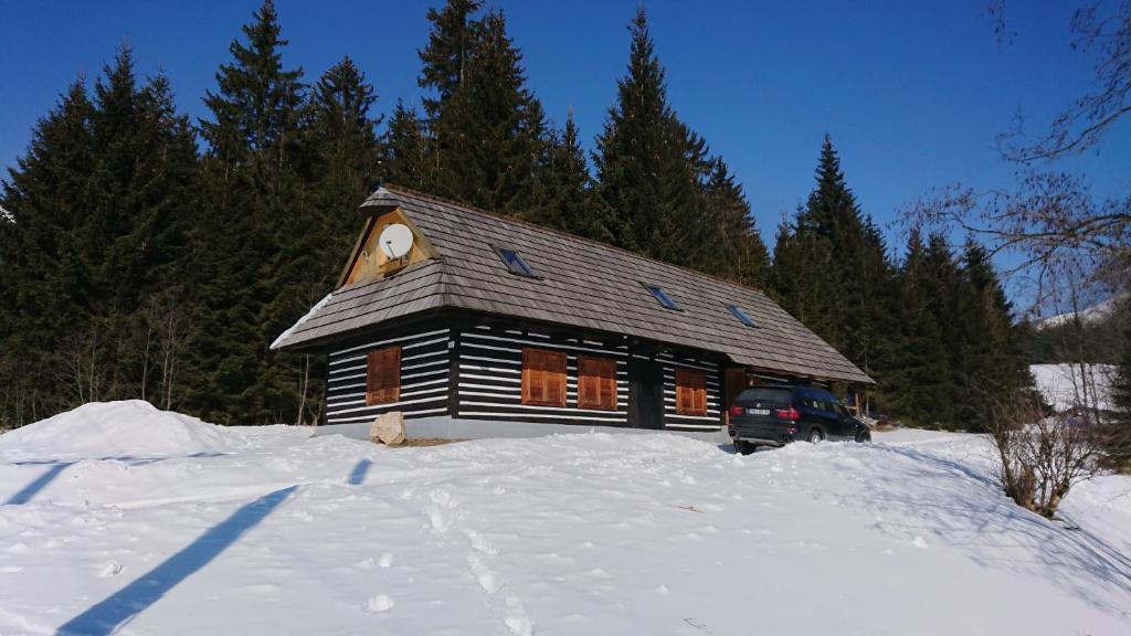 una cabaña de madera en la nieve frente a los árboles en Chata Telgart, en Telgárt