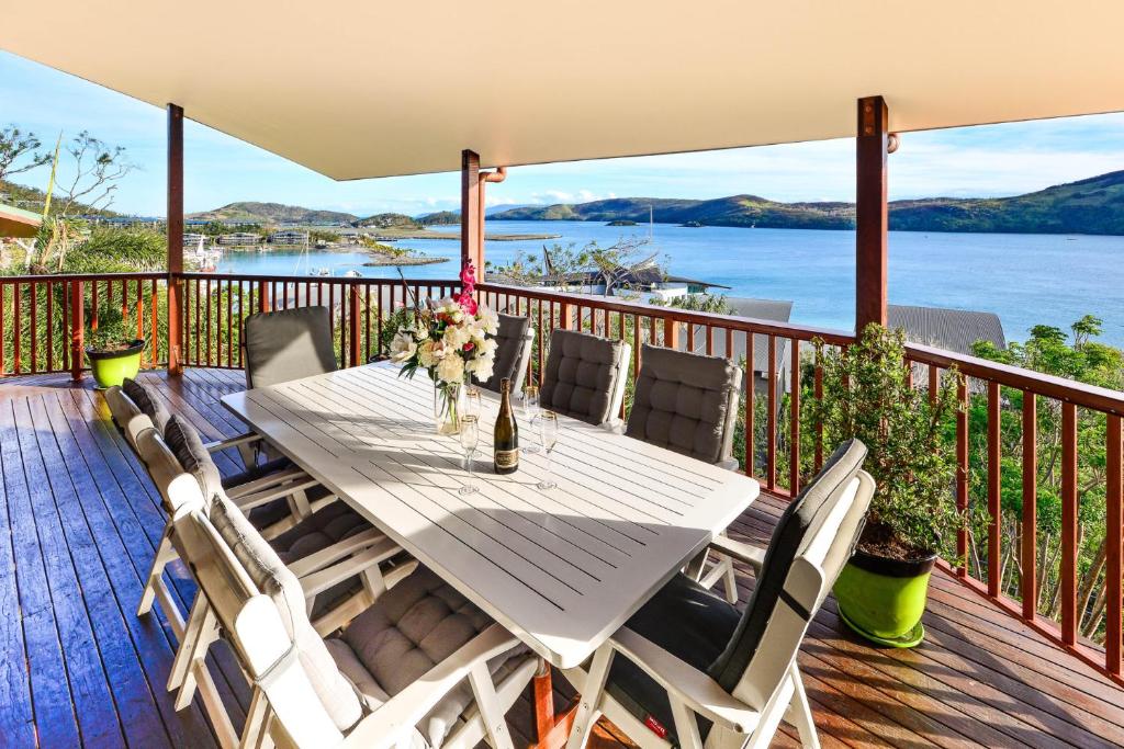 a table on a deck with a view of the water at Casuarina 16 - 3 Bedroom House With 180 Degree Ocean Views, Buggy & Valet Service in Hamilton Island