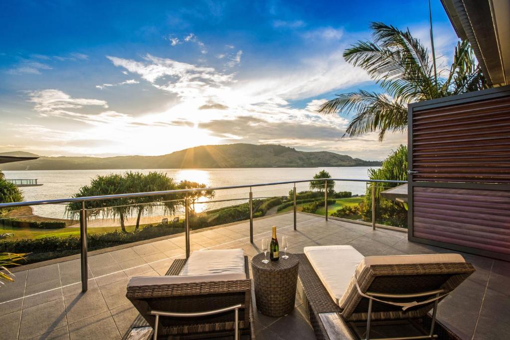 a balcony with a table and chairs and a view of the water at The Blue Marlin Yacht Club Villa 6 On Hamilton Island in Hamilton Island
