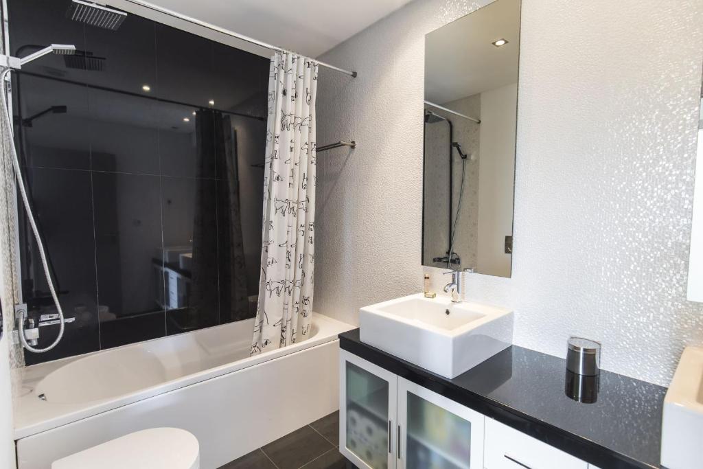 a white bathroom with a sink and a bath tub at modern flat in Estoril